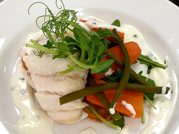 Cod fish in a white sauce with vegetables